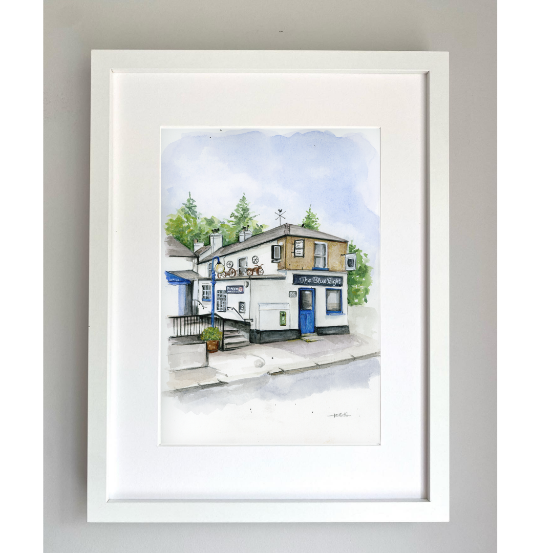 Framed artwork of The Blue Light Pub, Dublin with a colorful building and a blue door set against a white background.